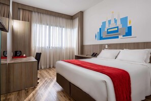 Ein Hotelzimmer mit Bett, Schreibtisch, Stuhl, Telefon und einer Wand mit einem Grafikdesign.