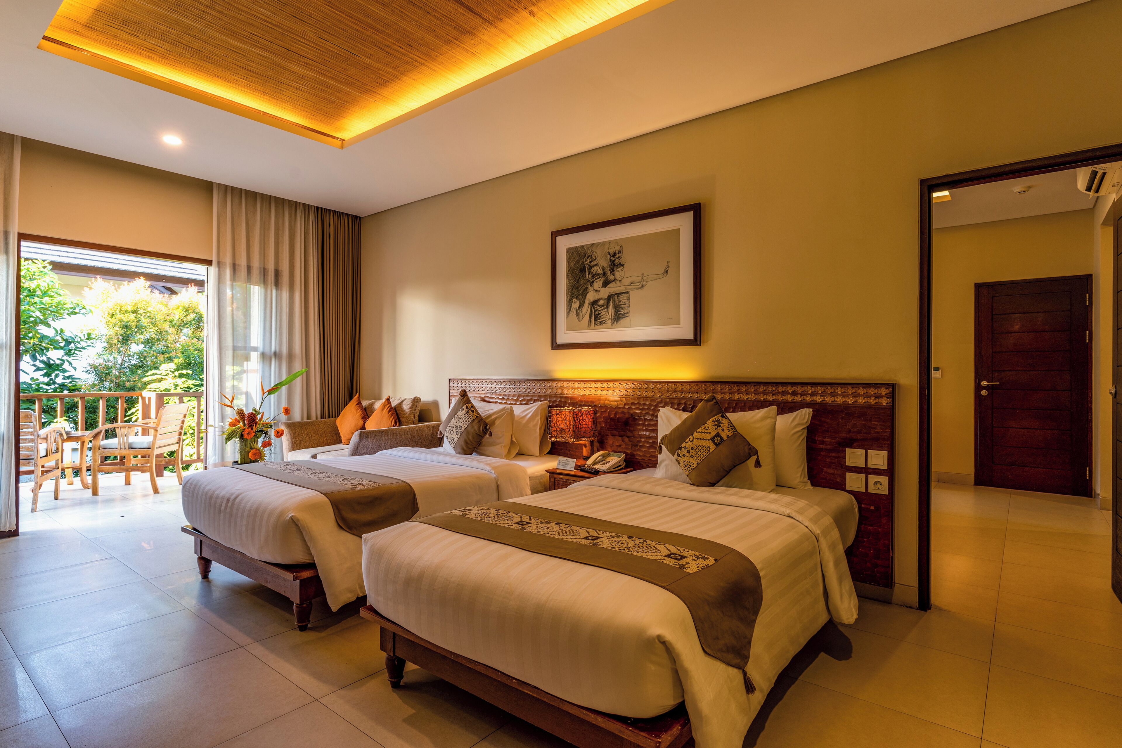 A hotel room with two beds, a wooden headboard, a framed artwork, and a balcony with outdoor furniture.