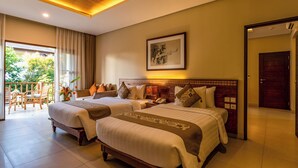 A hotel room with two beds, a wooden headboard, a framed artwork, and a balcony with outdoor furniture. - Radha Phala Resort and Spa (Ubud)