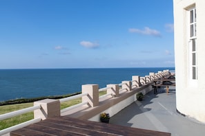 Ein Balkon mit Meerblick, ein weißes Gebäude und ein Holzterrasse.