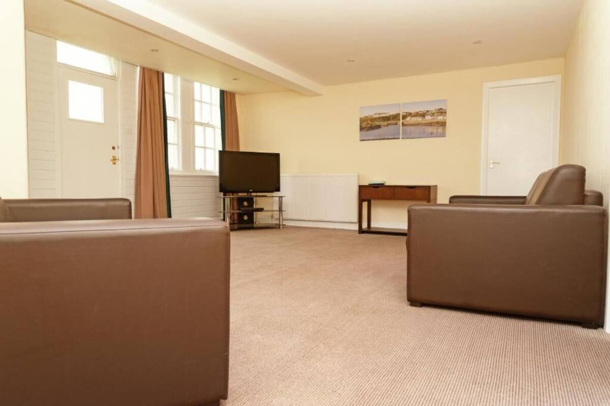 A living room with a television, two sofas, a small table, and a door.