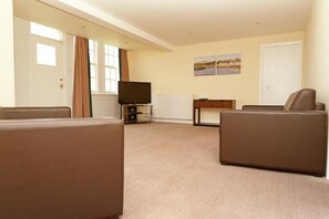 A living room with a television, two sofas, a small table, and a door. - Portpatrick Hotel (Stranraer)