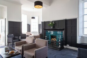 A living room with a fireplace, seating area, and a large window. - Portpatrick Hotel (Stranraer)