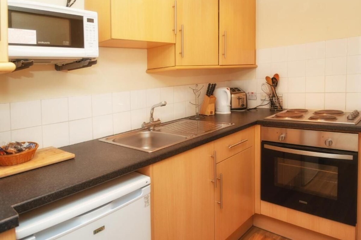 Eine Küche mit Holzausstattung, einer Mikrowelle, einem Spülbecken, einem Toaster und einem Geschirrspüler.