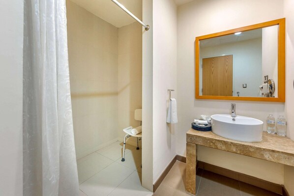 Een badkamer met een douche, toilet, wastafel en spiegel.