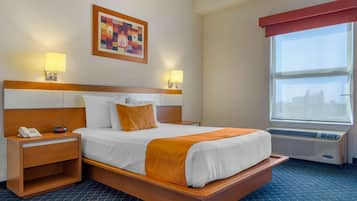 A hotel room with a bed, bedside lamps, a telephone, a painting, and a window with blinds.