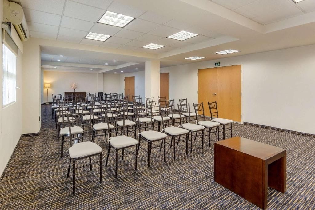 Een vergaderzaal met rijen stoelen, een spreekgestoelte en een vloerbedekking.