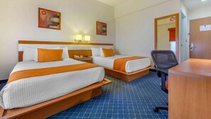 A hotel room with two beds, a desk, a chair, and artwork on the walls. - Greenwood Hotel Torreon (Torreón)