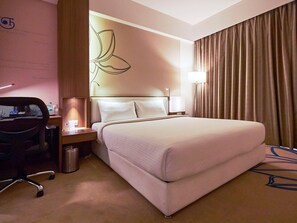 A hotel room with a bed, a desk with a chair, a lamp, and a trash bin. - Mercure Chennai Sriperumbudur (Tirukalukundram)