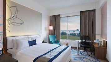 Een hotelkamer met een groot bed, een bureau, een stoel en uitzicht op de omgeving.