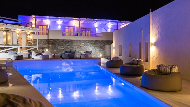 A swimming pool area with lounge chairs and a stone wall. - Anamar Kea (Kea)