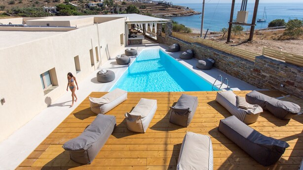 Una piscina en la azotea con sillones de descanso y vistas al mar.