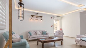 Una sala de estar moderna con un sofá, sillones, una mesa de centro e iluminación colgante.