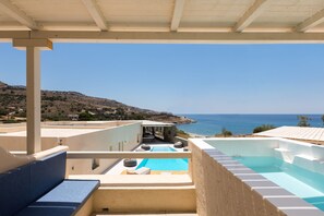 A rooftop pool area with a view of the sea, a covered seating area, and a pool with a blue tint. - Anamar Kea (Kea)