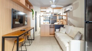 Eine moderne Küche mit eingebautem Fernseher, Holzschränken, einem weißen Sofa und einem Deckenventilator.