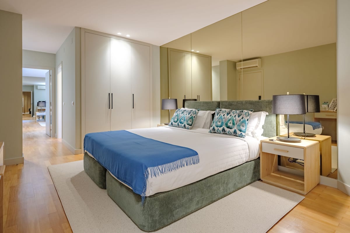 Un dormitorio con cama, mesitas de noche, armario y un espejo grande.
