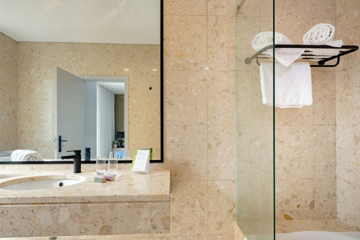 Un baño con lavamanos de mármol, cabina de ducha con mampara de vidrio y bañera.
