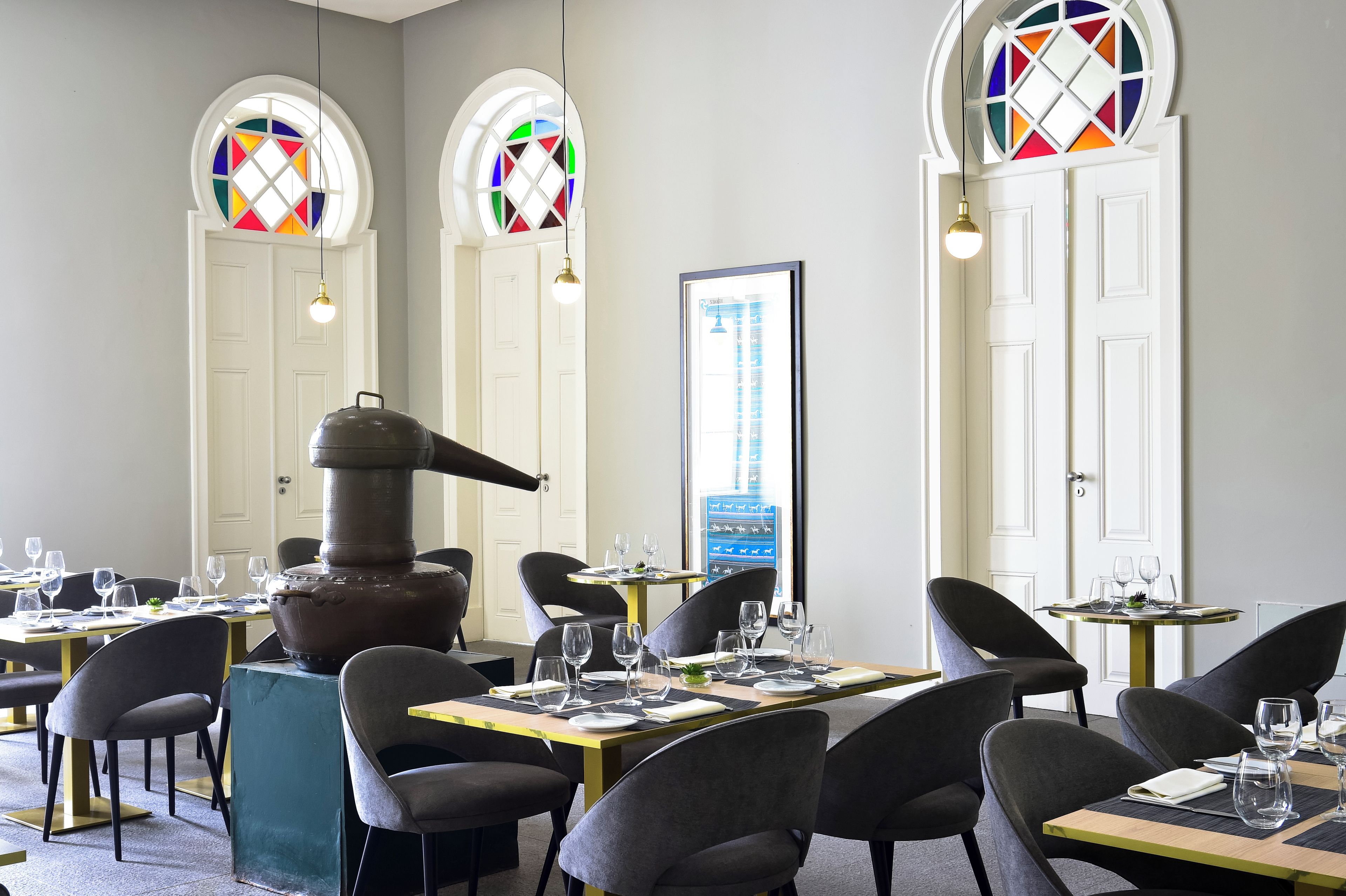 A restaurant with round tables, chairs, and a large stove.