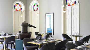 A restaurant with round tables, chairs, and a large stove.