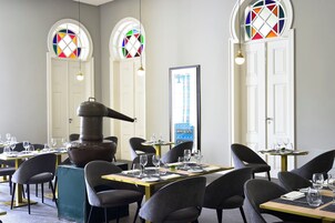 Um restaurante com mesas redondas, cadeiras e uma lareira grande.