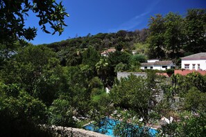 A hillside view with a swimming pool, surrounded by lush greenery and a few buildings. - Pure Monchique Hotel by Unlock Hotels (Monchique)
