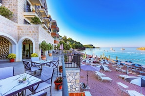 Un hotel frente al mar con terraza exterior, fachada de piedra y vistas al océano.