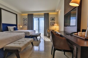 A hotel room with two beds, a desk, a chair, a lamp, and a TV. - California (Sveti Stefan)