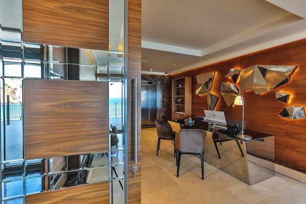 Un interior moderno con un mostrador de recepción de madera, una computadora portátil y un comedor con sillas.