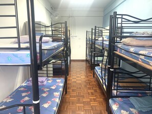 A dormitory room with bunk beds, wooden flooring, and a white wall with a power outlet. - Spot ON 89872 Kuantan Backpackers (Kuantan)