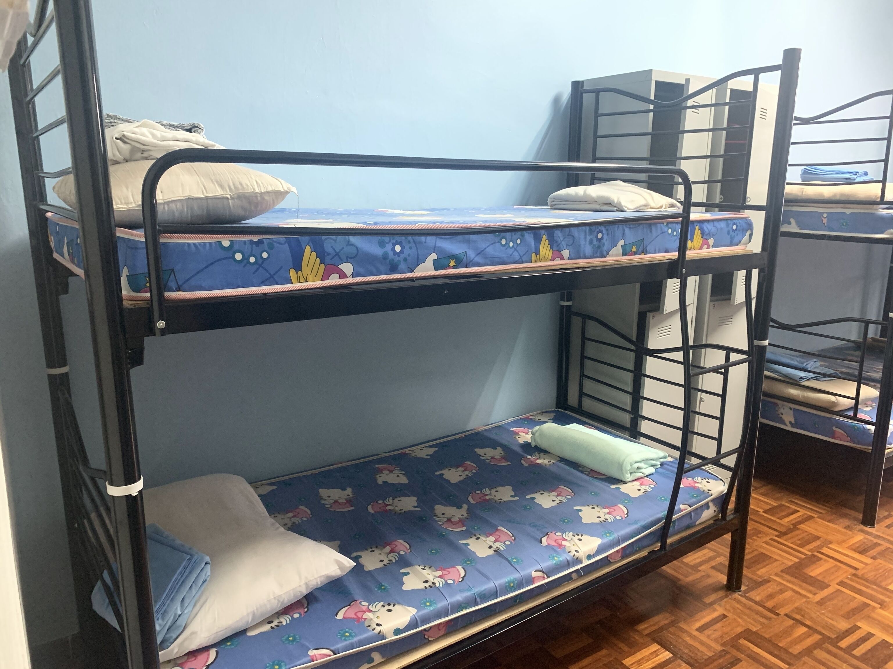 A bunk bed room with a blue patterned mattress, pillows, and a wooden floor.