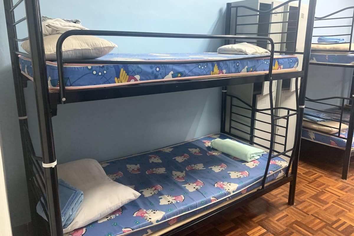Dormitorio con literas, colchón azul estampado, almohadas y suelo de madera.