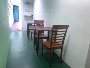 Un pasillo con una mesa de comedor y sillas, una cortina azul y un panel eléctrico en la pared.