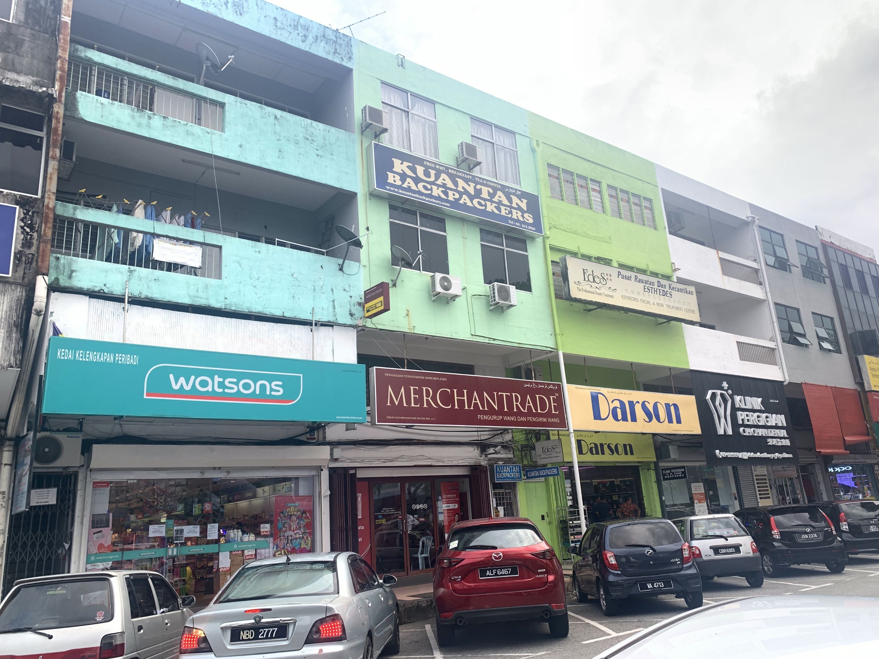 A street view with various shops including a pharmacy, a tea shop, and a beauty salon.