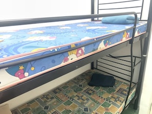 Un lit superposé avec un matelas bleu orné de personnages de dessins animés, un sol à motifs et une structure en métal.