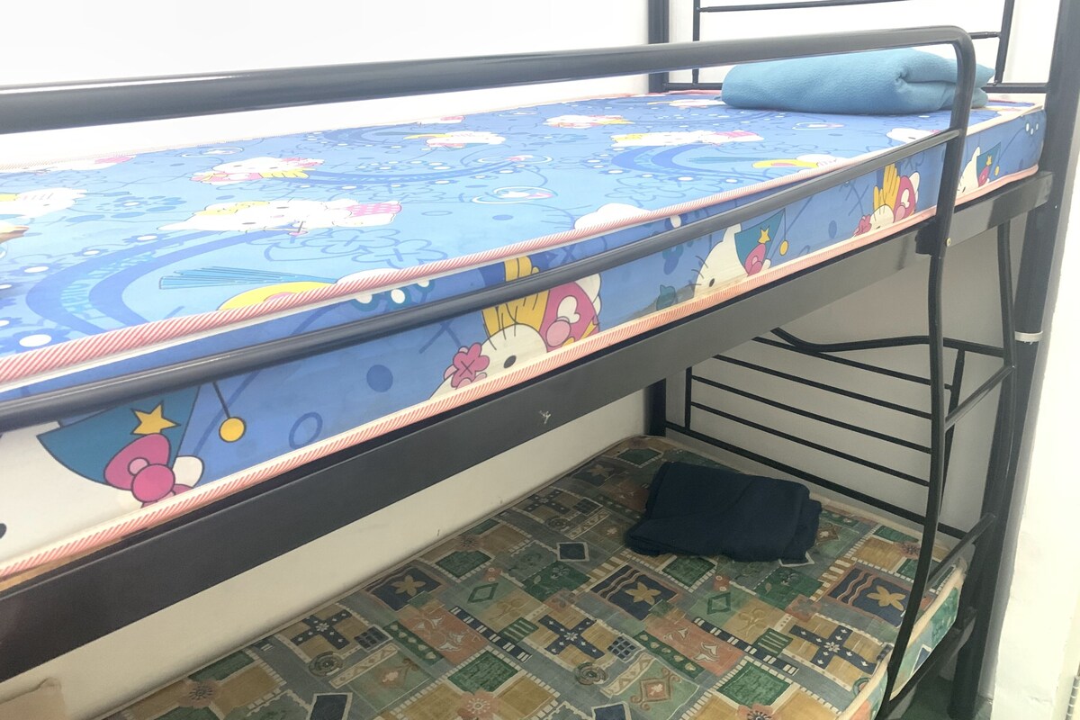A bunk bed with a blue mattress featuring cartoon characters, a patterned floor, and a metal frame.