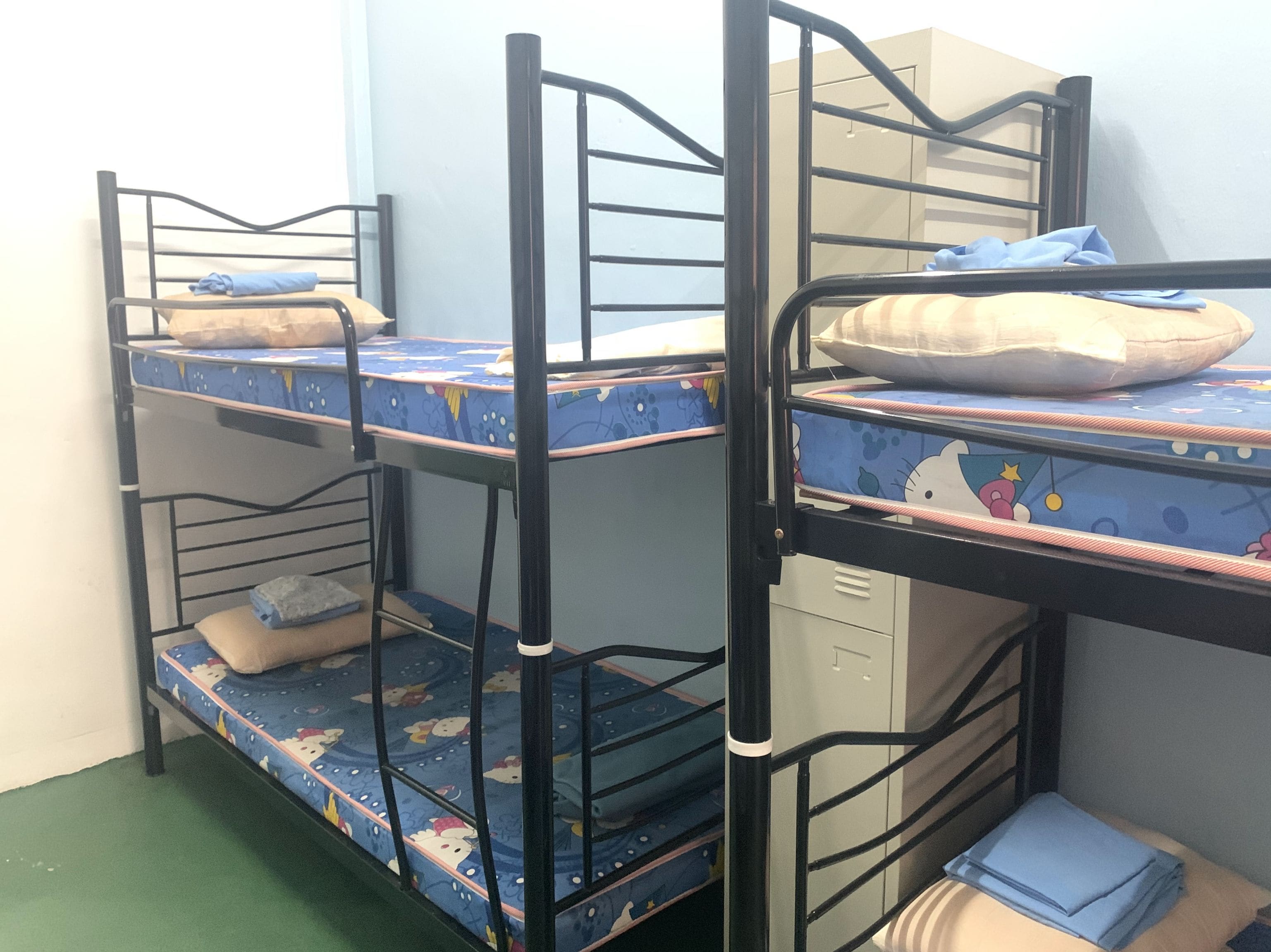 Habitación con literas, un colchón azul con personajes de caricaturas, una almohada blanca y un pequeño armario.