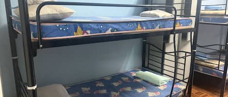 A bunk bed room with a blue patterned mattress, pillows, and a wooden floor.
