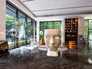 A modern lobby with a large sculpture, a bookshelf, and a coffee machine. - Paco Hotel Taojin Metro Guangzhou (Guangzhou)