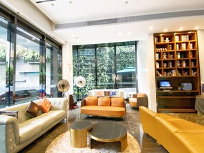 A modern living room with a sofa, armchairs, a coffee table, a bookshelf, and a large window with a view of greenery. - Paco Hotel Taojin Metro Guangzhou (Guangzhou)