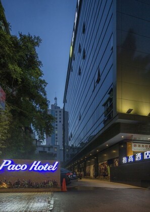 A hotel entrance with a neon sign, a paved driveway, and a building with multiple floors and windows. - Paco Hotel Taojin Metro Guangzhou (Guangzhou)