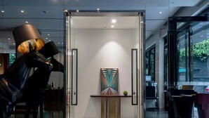 A modern interior with a glass door entrance, a sculpture of a horse, and a minimalist art piece on a console table. - Paco Hotel Taojin Metro Guangzhou (Guangzhou)