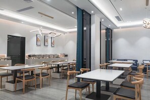 A modern dining area with tables and chairs, a counter with a coffee machine, and framed artwork on the wall. - Paco Hotel Taojin Metro Guangzhou (Guangzhou)