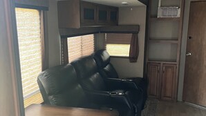 Ein kompaktes Wohnmobil-Interieur mit einer Sitzecke, einer kleinen Küchenzeile und einem Fenster, das für natürliches Licht sorgt.