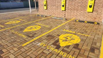 A parking area with yellow 'EV CHARGING' markings and RAA charging stations.