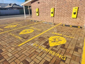 En parkeringsplads med gule markeringer for 'EV CHARGING' og RAA opladningsstationer.