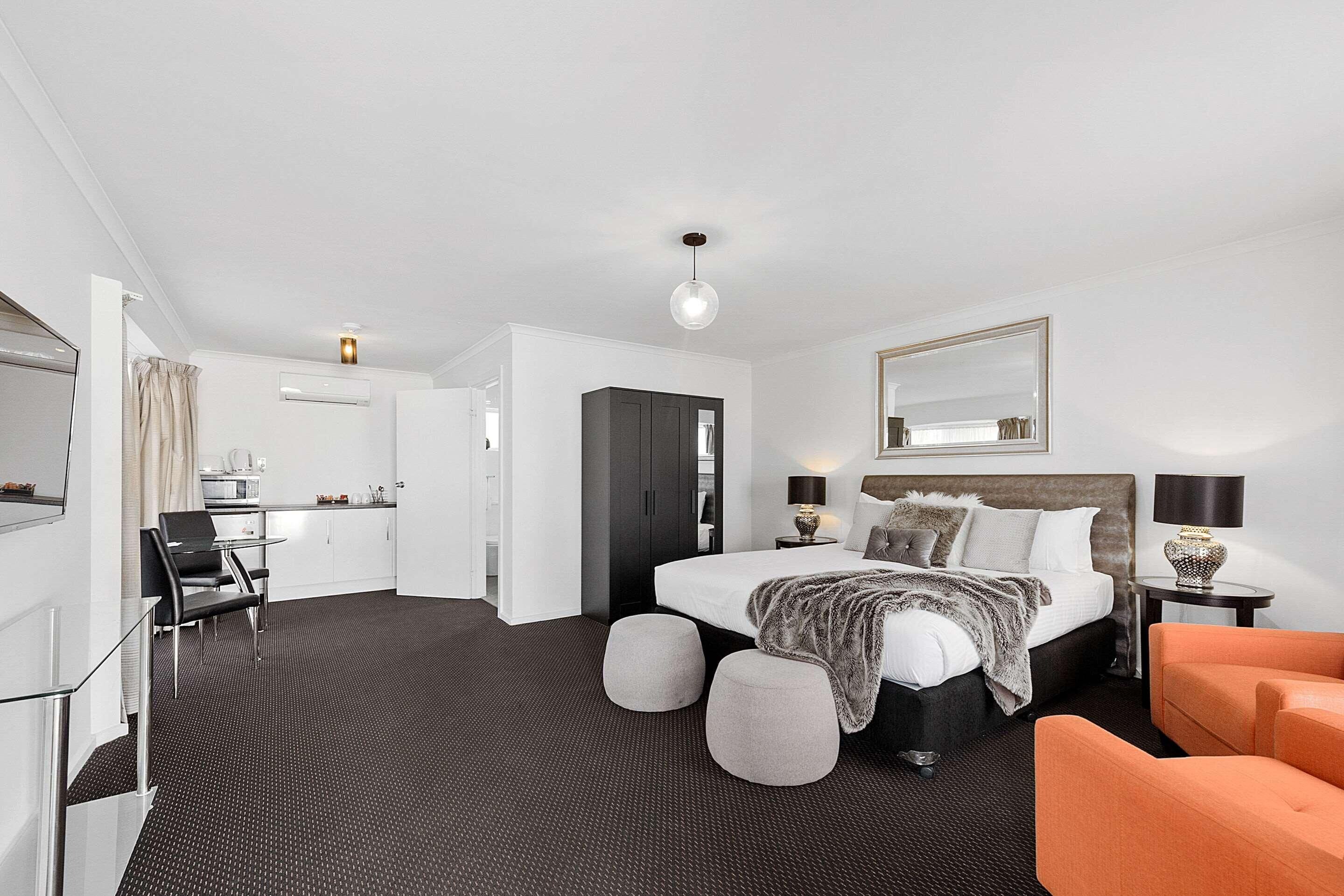 Ett modernt hotellrum med en säng, sängbord, ett skrivbord och en stol.