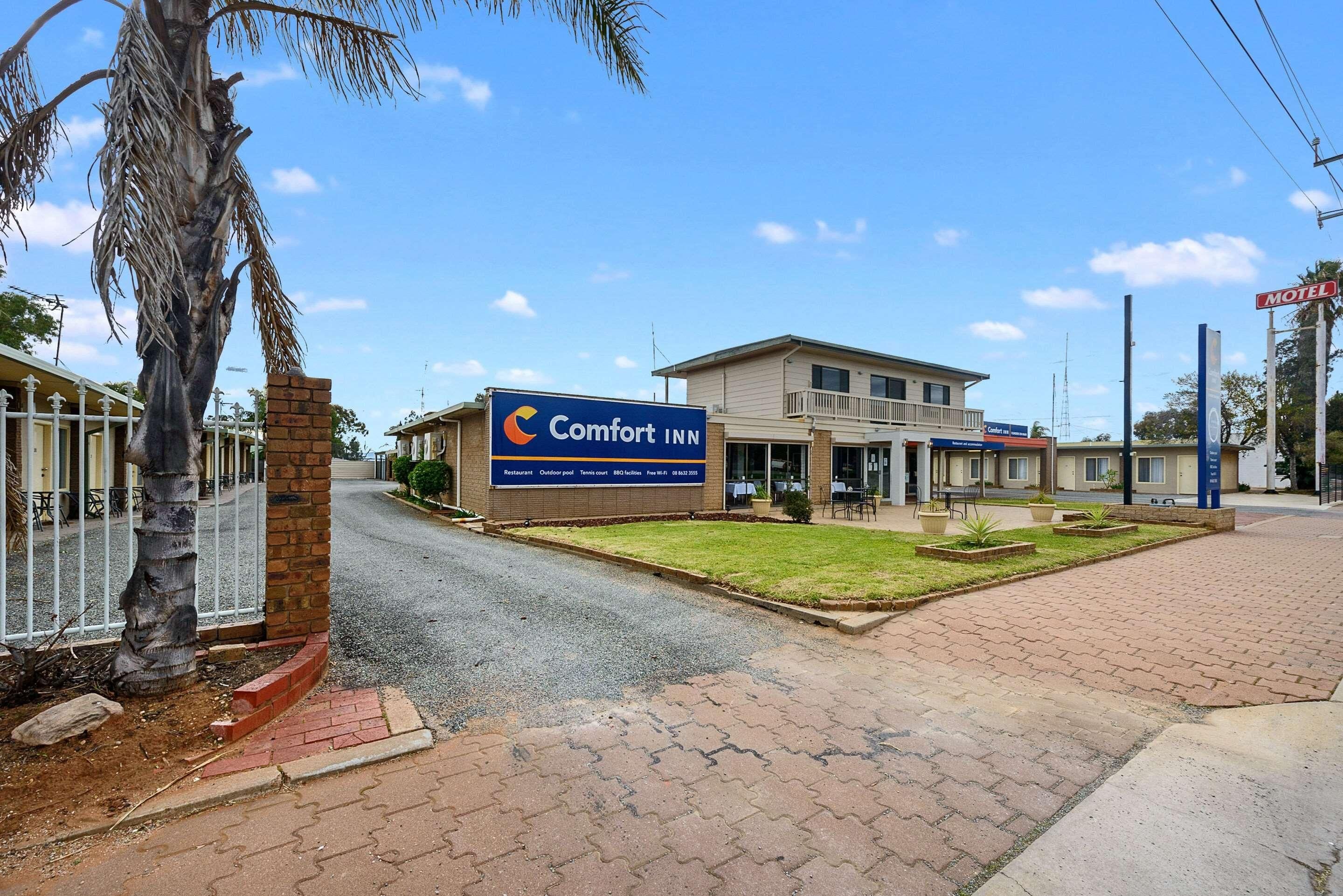 A Comfort Inn with a signboard, a paved entrance, and a building with a balcony.