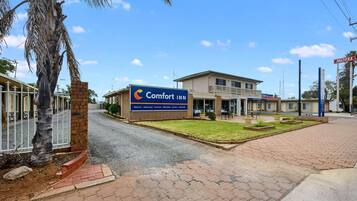 A Comfort Inn with a signboard, a paved entrance, and a building with a balcony.