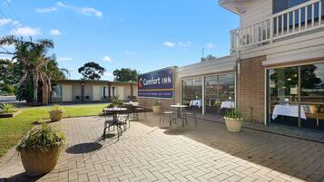 A Comfort INN with a patio area featuring outdoor seating and potted plants.