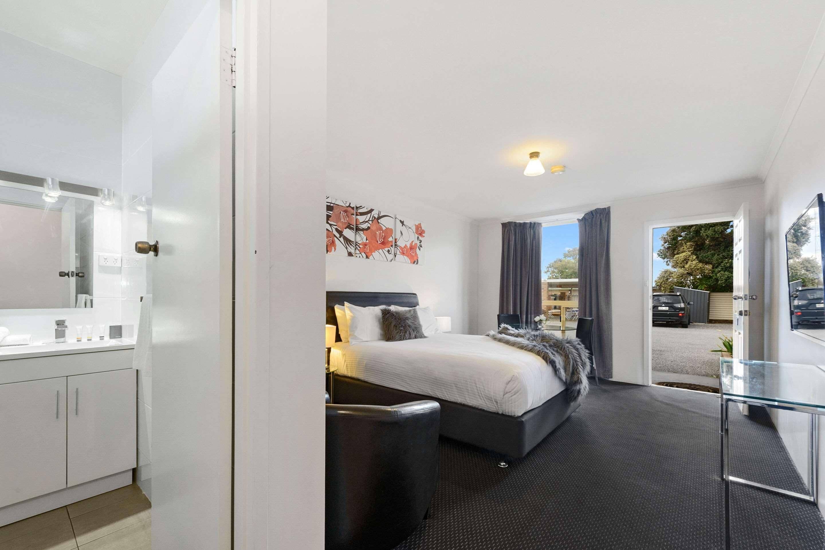 A modern hotel room with a bed, bedside table, and a view of the outside.
